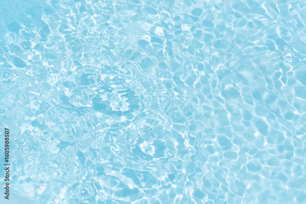 Obraz premium Blue water with ripples on the surface. Defocus blurred transparent blue colored clear calm water surface texture with splashes and bubbles. Water waves with shining pattern texture background.