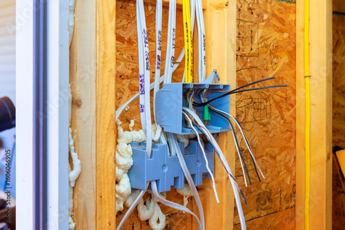 Workers are installing junction box wires in wall during home renovations in neighborhood.