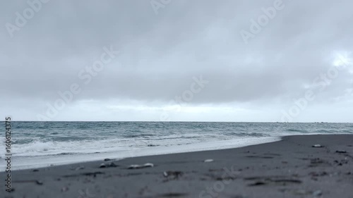 曇り空と白い波が打ち寄せる初夏の波打ち際