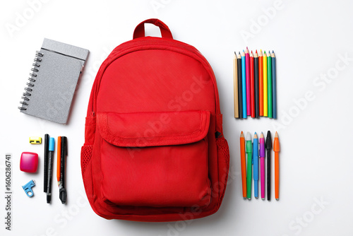 Top view of a red backpack with school supplies on a white background, a flat lay concept for back to school and education.