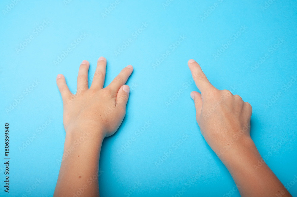 Small child's hands on a blue background, top view. Skin care, family, education, and playing template concept. Small child's hands on a blue background, top view. Skin care, family, education, and playing template concept.