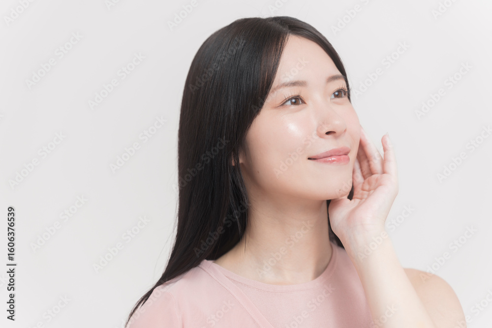 顔に手をあてて微笑む若い女性 顔に手をあてて微笑む若い女性
