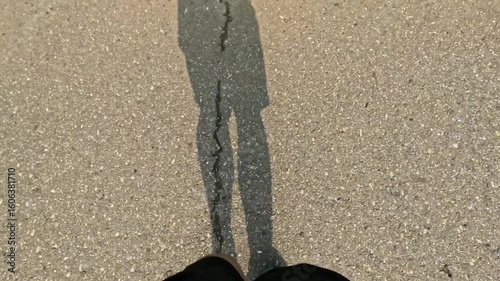 point of view of man foot running on asphalt road with shadow in the morning