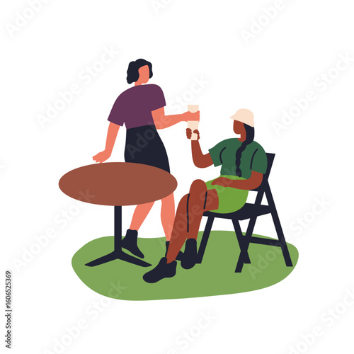 Young women friends sitting in chairs at table outdoors. Girls with drinks, c...