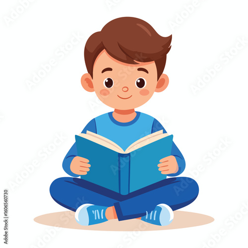 A young boy sitting cross-legged, absorbed in reading a blue book.