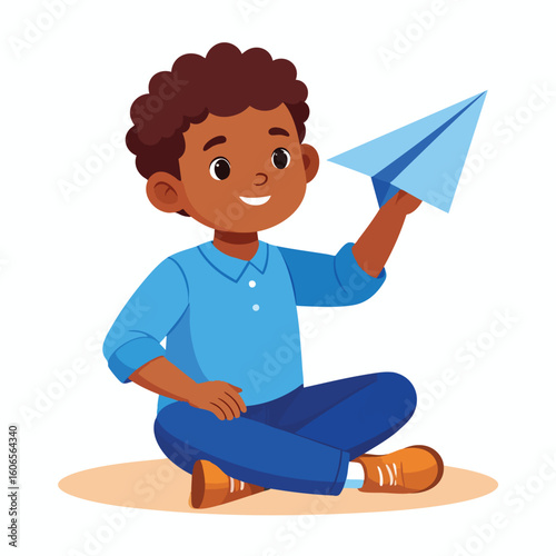 A young boy sits and holds a paper airplane, happy and ready to fly.