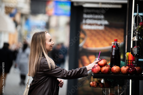 Smiling woman buying pomegranate juice from street vendor