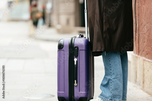 Close up of traveler with suitcase on city sidewalk