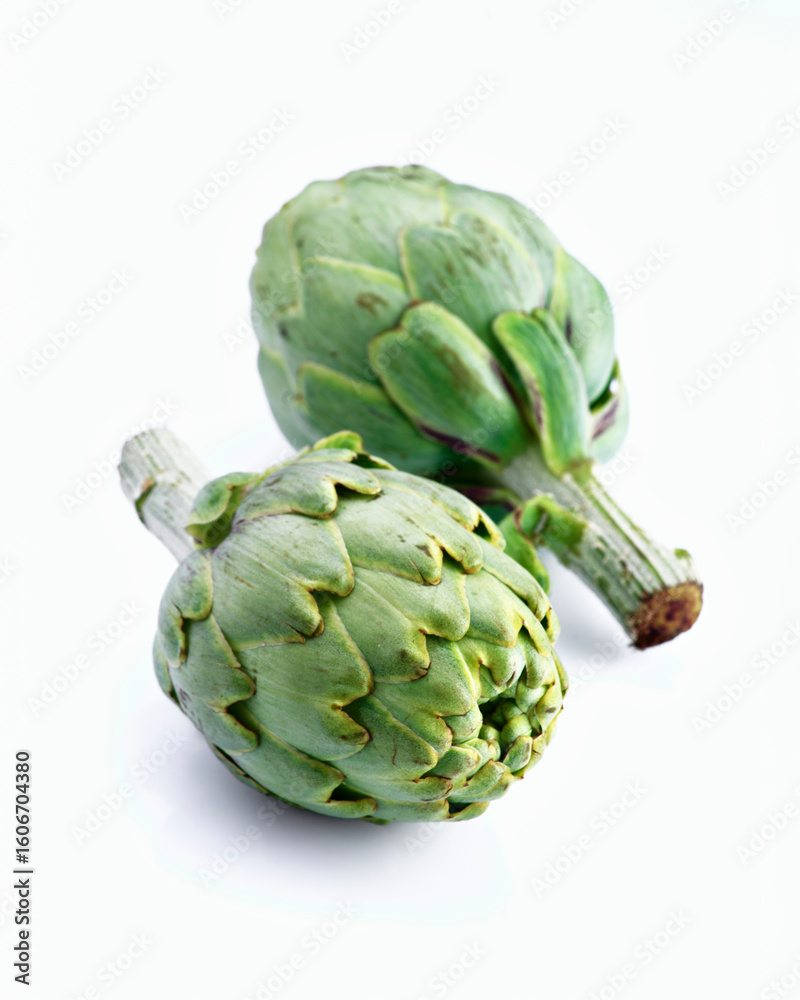 Obraz premium Two fresh artichokes resting on white background