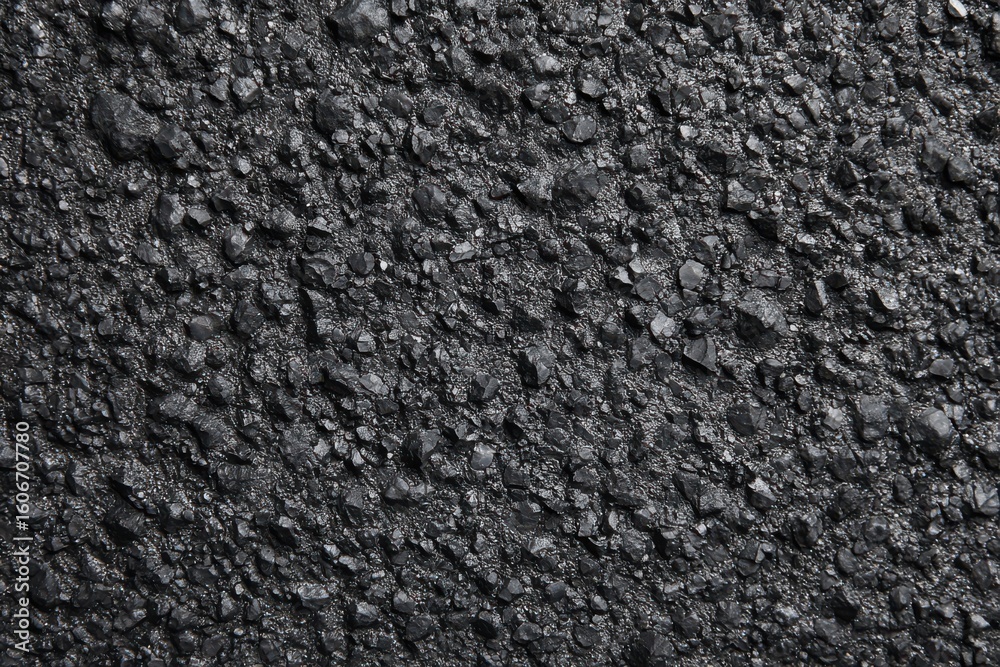 Fototapeta premium Dark asphalt close-up texture for urban exploration, road construction projects, or automotive enthusiasts seeking detailed pavement imagery in diverse environments