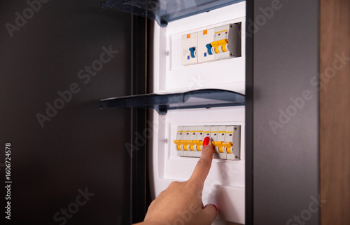 A woman's hand turns on the electricity on an automatic electrical control panel. Automatic safety shutdown of electricity, industry