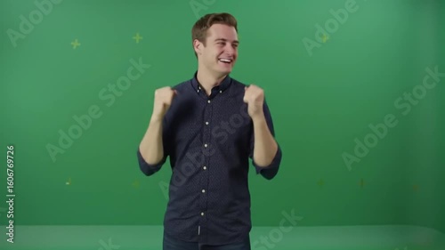 Man in blue shirt celebrating with fists raised against a green screen backdrop with gold star accents