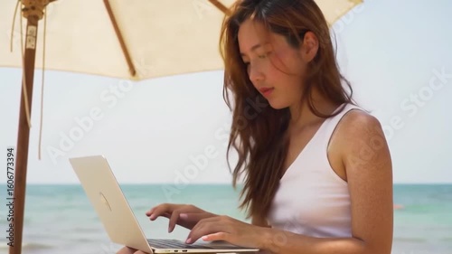 Woman working on laptop on a beach