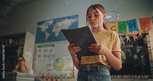 Primary School Girl Holding Notebook Speaking, Showcasing Knowledge of Ecology in Front of Classmates and Teacher. Smart Pupil Presenting Homework During Environmental Science Lesson. Dolly Shot.
