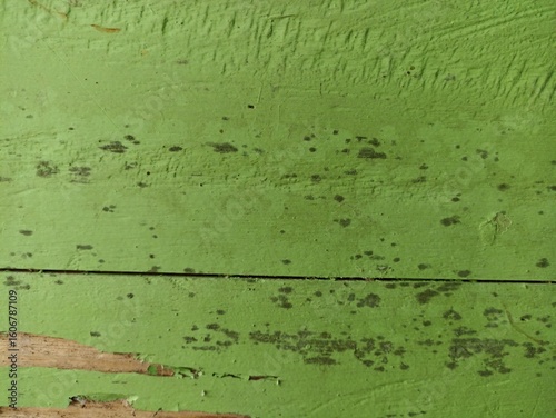 Aged Green Wooden Planks with Peeling Paint and Black Spots. Close-up of old green painted wood with cracks, black mildew spots, and peeling surface. Rustic texture for backgrounds or vintage themes