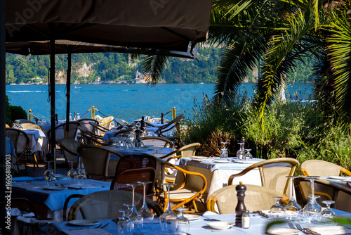 Cernobbio, Lake Como, Lombardy - July 7, 2025: View of Lake Como from a restaurant in Cernobbio. Tables are set ready to welcome tourists.