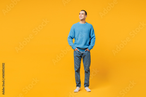 Billede på lærred Full body young smiling happy cheerful middle eastern man wearing blue sweatshirt casual clothes stand look aside on area isolated on plain yellow orange background studio portrait