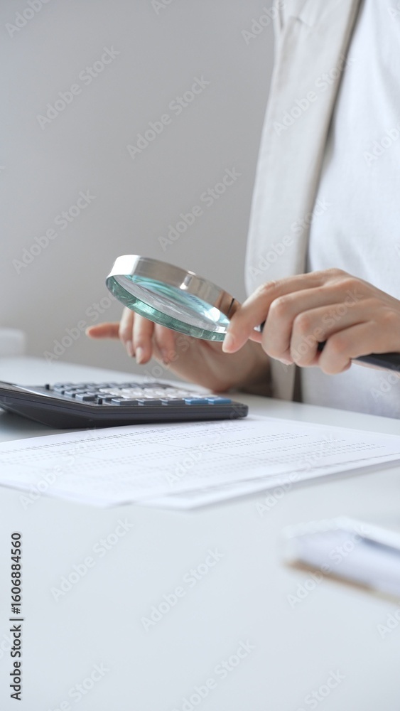 Fototapeta premium Financial professional analyzing company reports with magnifying glass, checking detailed metrics and verifying accounting precision on desk workspace. Audit and taxes in business