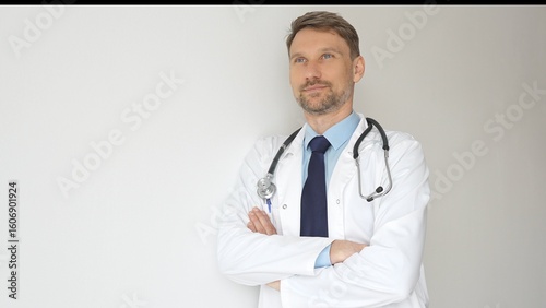 Foto Confident male physician wearing stethoscope and white coat, standing with crossed arms and gazing thoughtfully, representing medical professionalism and expertise