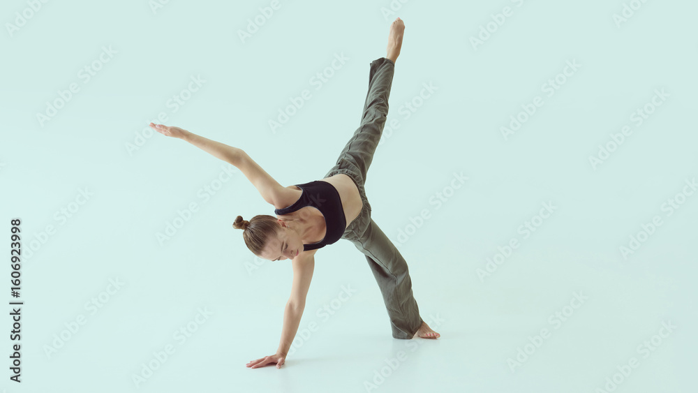 Fototapeta premium Female dancer holding one-arm floor balance with extended leg and intense focus. Concept of body discipline, strength control, performance and contemporary technique.