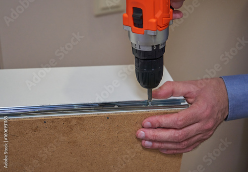 Wallpaper Mural cordless screwdriver tightening guides in furniture, locksmith with the help of a screwdriver installs the mechanism of guides on a drawer, the process of assembling furniture Torontodigital.ca