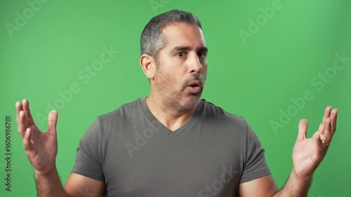 Man with gray hair and v neck shirt expressing surprise with open mouth and raised hands on green screen