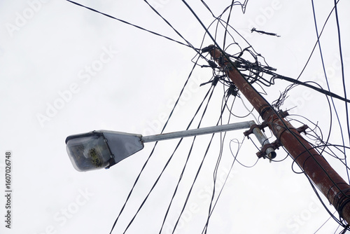 Rusty street lamp with tangled power lines overhead