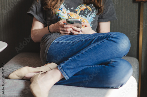 Bilde på lerret Young woman scrolling on a mobile phone on a couch