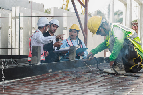 Tableau sur toile Worker welding rebar on metal mold while supervisors discuss production plan in background, showing collaboration in concrete element manufacturing