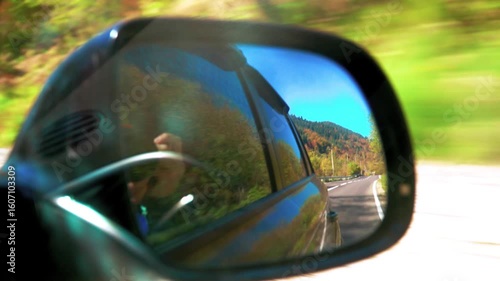 Colorfull autumn mountain forest mirror of a moving car