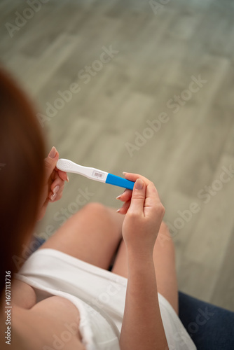 A woman holds a pregnancy test with two stripes in her hands