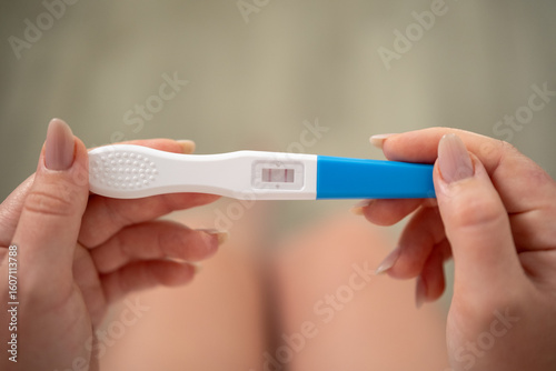 Close-up of female hands holding a pregnancy test with a positive result.