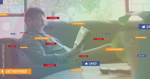 Man reading paperback book on sofa in living room, with TV remote and notification graphics