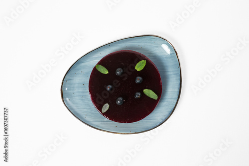 Pelamushi, low-calorie blackcurrant mousse cake on a plate on a white background