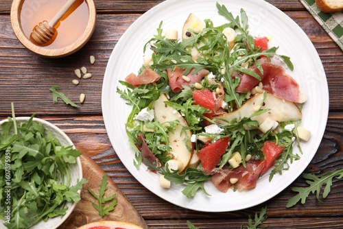 Papier peint Tasty salad with arugula and prosciutto served on wooden table, flat lay