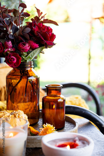 Autumn cozy mood composition on the porch. Pumpkins, autumn flowers, candles on the tray vertical photo
