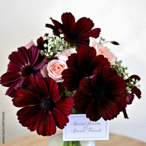 Flowers with velvety burgundy petals and a dark brown center, displayed in an elegant glass vase.