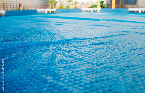 The blue coating of the pool, reflecting sunlight, emphasizes summer recreation and pool maintenance.