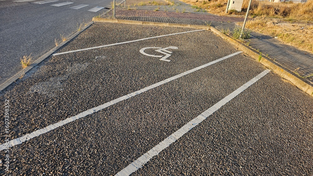 Fototapeta premium Handicapped Parking Space with Worn Asphalt and Roadside Weeds