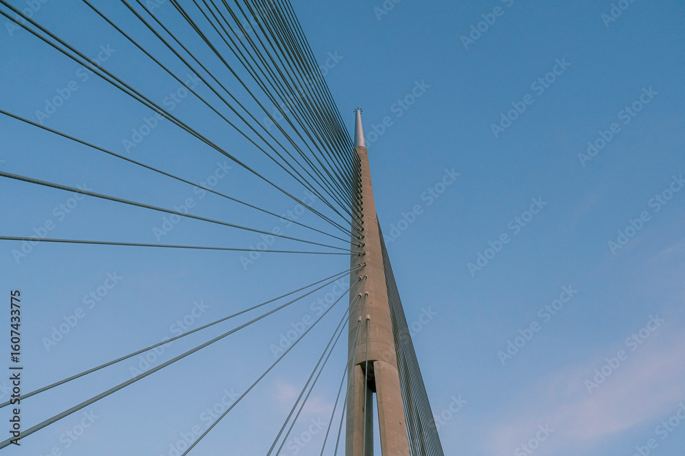 Minimalist view of a modern cable-stayed bridge against clear blue sky, looking up from below Minimalist view of a modern cable-stayed bridge against clear blue sky, looking up from below