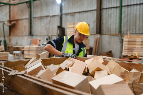 Photos Male staff member enjoying timber work, holding a square wooden piece inside production warehouse, contributing to pallet material preparation and sustainable reuse planning