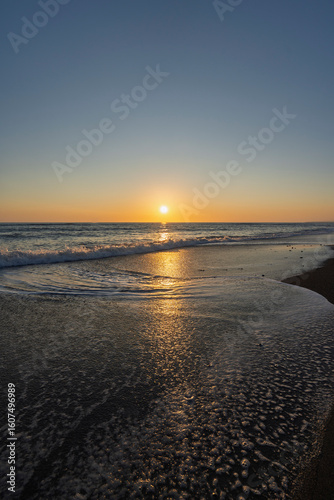 Fototapeta Naklejka Na Ścianę i Meble -  golden sunset over the Mediterranean Sea with small waves on sandy beach in Marina di Bibbona in Tuscany in Italy