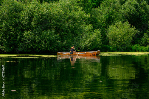 Photography Man solo paddling a canoe on a pond on the Toronto Islands with lush vegetation