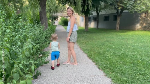Mother and child exploring plants along park path

