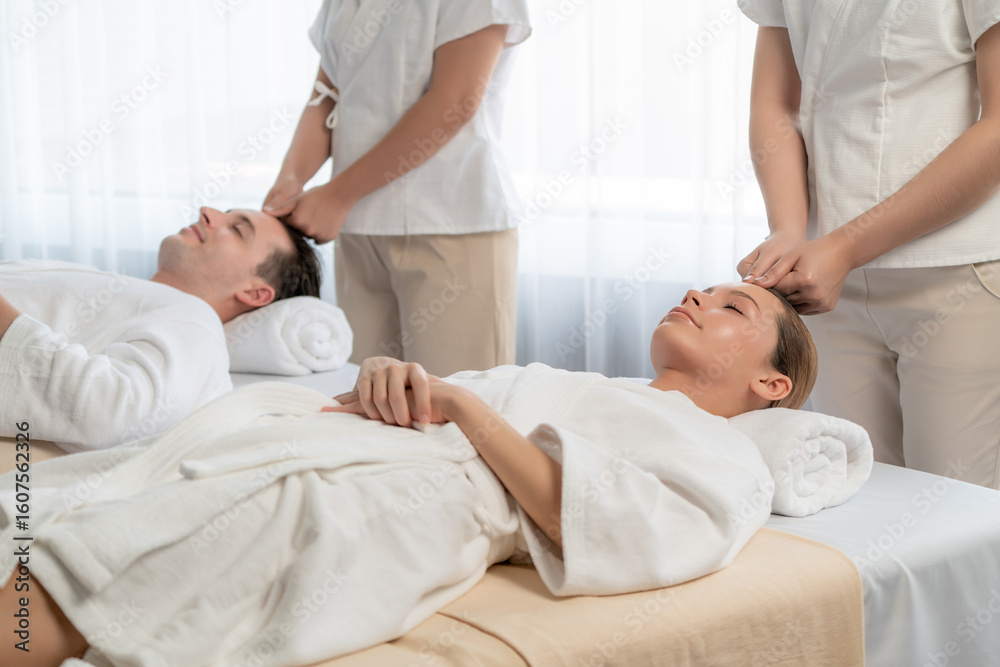 Obraz premium Caucasian couple enjoying relaxing anti-stress head massage and pampering facial beauty skin recreation leisure in dayspa modern light ambient at luxury resort or hotel spa salon. Quiescent