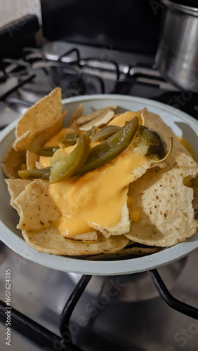 Vertical photo of a plate of nachos with melted yellow cheese.