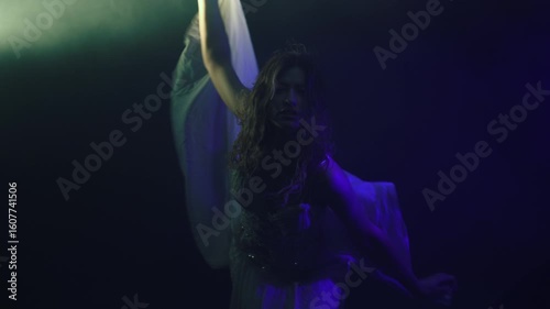 Enchanting dancer in flowing white, captured in semi-darkness with dramatic backlighting