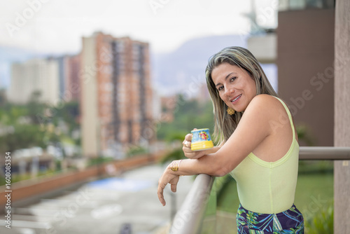 Mujer disfrutando de una taza de café en el balcón con vista a la ciudad
