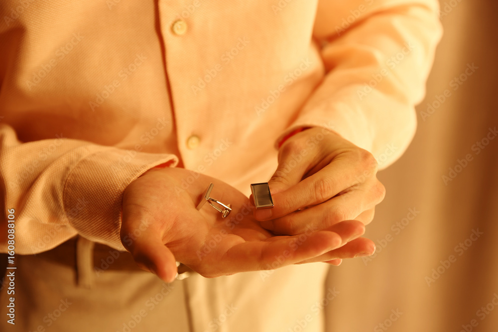 Fototapeta premium Man with cufflinks getting ready indoors, closeup