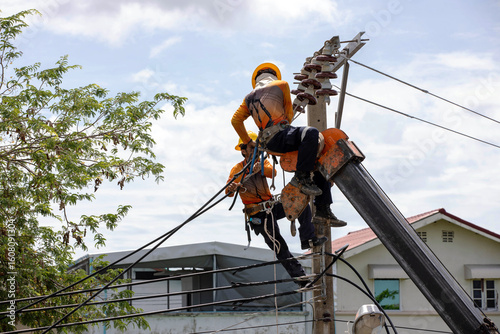 Tableau sur toile Two electric utility workers performing high-voltage maintenance on a power pole
